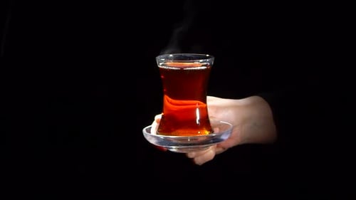 Femme offrant un verre de thé noir