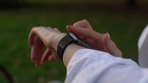 Close-up of young woman using sports smart watch and checking health reading, slow motion.