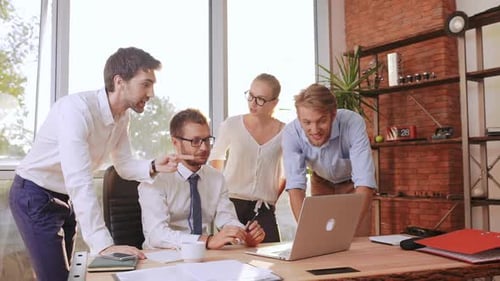 Four Professionals Collaborating on Laptop in Office