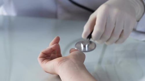 Medical Professional Takes Patient Pulse with Stethoscope