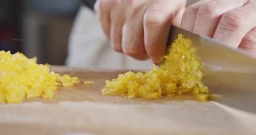 Slow motion close up of a chef knife slicing a yellow bell pepper