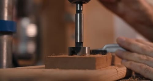 Woodworker Drills Holes in Wooden Plank with Drilling Machine in Slow Motion Carpentry at Workshop