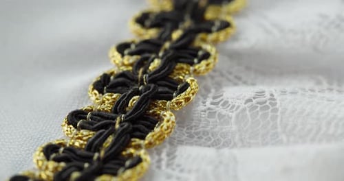 Weiße Spitze mit schwarzem und goldenem Dekor in Nahaufnahme