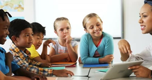 Teacher teaching school kids on digital tablet in classroom