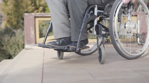 Side View Close-up of Wheelchair with Unrecognizable Old Man Rolling To Stairs. Concept of Ramp
