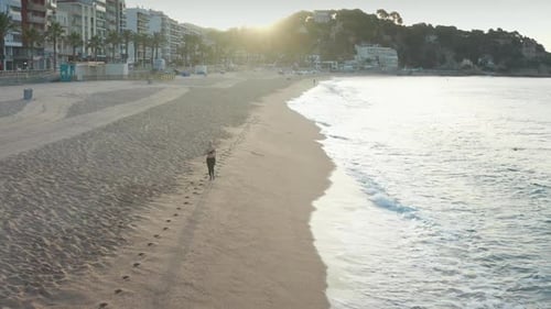 Drone View of Sporty Female Running Along Beach