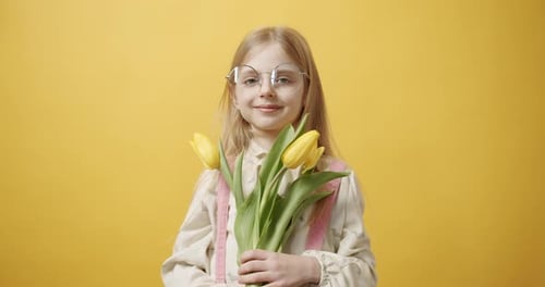 Smiling Girl Offering Yellow Tulips Bouquet on Yellow