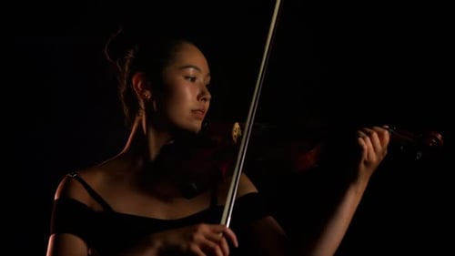 Young Adult Plays Violin in Dark Room