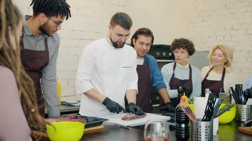 Professioneller Koch beim Fleischschneiden während der kulinarischen Meisterklasse in der Kochschule