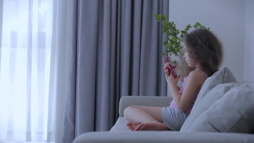 Girl Using Mobile Phone on Sofa Indoors