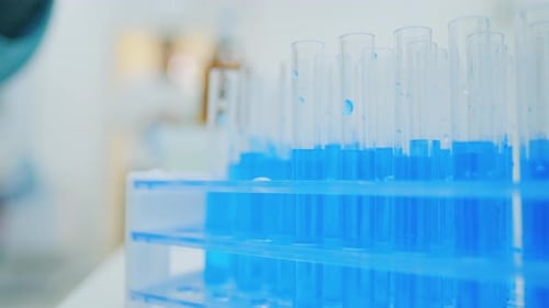 Adding Blue Liquid to Test Tubes in Lab