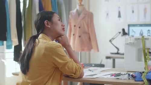Back View Of Asian Female Designer With Sewing Machine Thinking While Designing Clothes