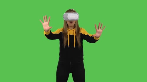 Chica moderna con capucha amarilla con auriculares de realidad virtual o gafas 3D. Pantalla verde