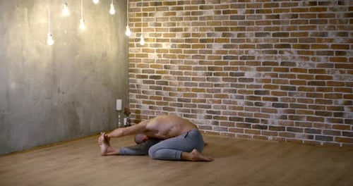 A Person Practicing Advanced Yoga. Strong Man Performs Exercises in the Studio