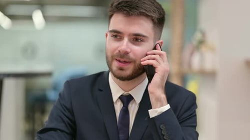 Young Adult Man Talking on Mobile Phone in Office