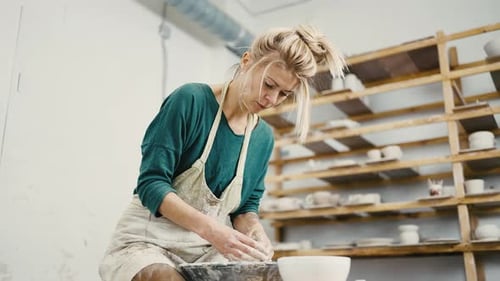 Female Potter Sitting at Pottery Workshop and Making Ceramic Pot on Wheel Below View Slow Motion