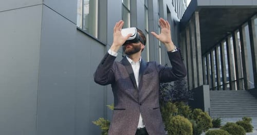 Businessman in Augmented Reality Goggles Working Outdoors Near Modern Urban Building