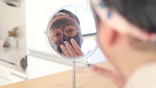 Woman Applying Beauty Mask Looking in Mirror