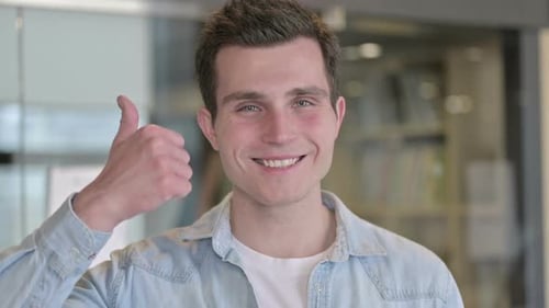 Porträt eines erfolgreichen jungen Designers, der Daumen hoch zeigt