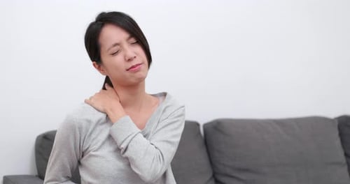 Young Woman Massaging her Shoulder in Discomfort