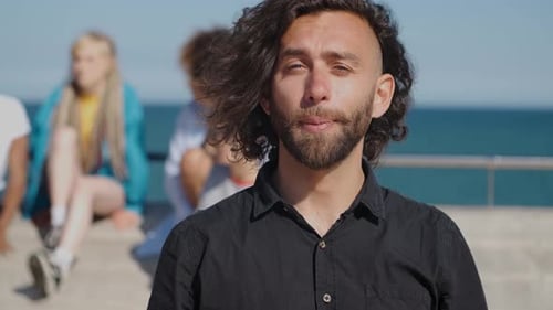 Smiling Young Man with Friends on Sunny Beach
