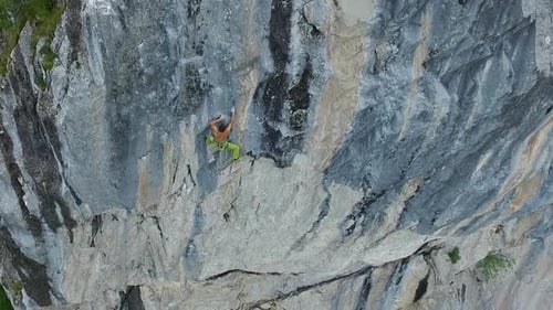 Aerial drone view of a man rock climbing up a mountain