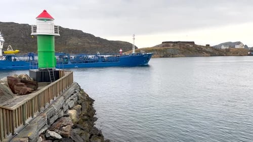 People at the green lighthouse on the background of the city and mountains. Port.Small boat passing