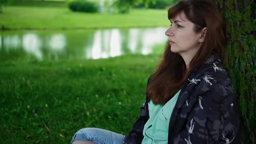 Sad Woman Sitting in the Park Near a Tree and Thinking About Something Memories