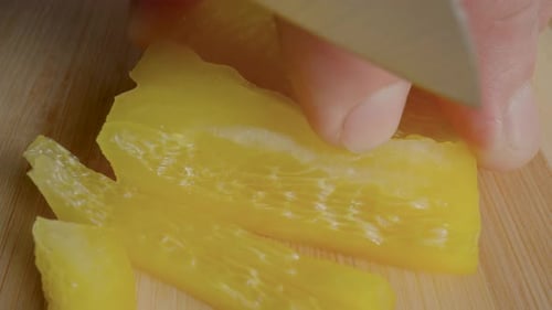 Slicing a Yellow Pepper on Wooden Cutting Board
