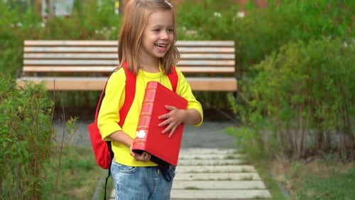 Girl Holds Book Smiles and Laughs