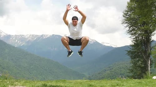 Happy Man Jumping at Mountains To Clouds Sky. Lifestyle Travel Emotional Euphoria Success Concept