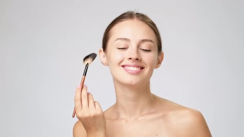 Young Woman Applying Makeup with Brush