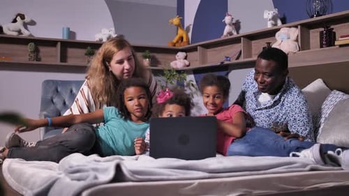 Family Enjoys Laptop Together on Bed in Bedroom