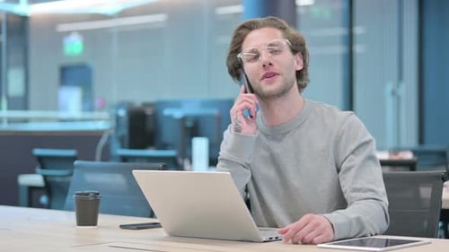 Young Adult Man Talking on Phone in Office