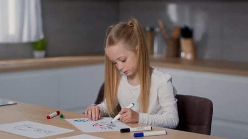 Child Drawing at Table with Colorful Markers