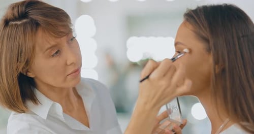 Makeup Artist Completes Makeup, Woman Thanks Makeup Artist. Beauty Studio. Portrait View.