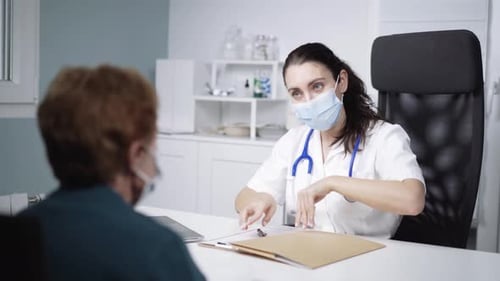 Physician sharing document and speaking with unrecognizable patient in clinic