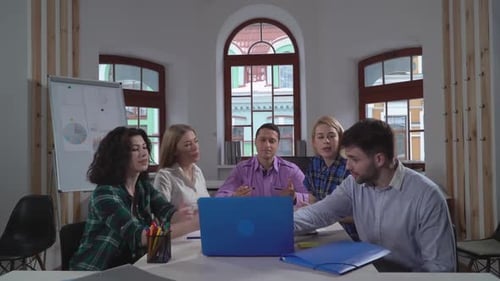 Team Discussing Project Around Laptop in Modern Office