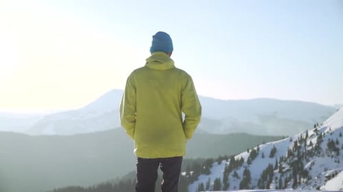Man Standing on Snowy Mountain Peak on Winter Day