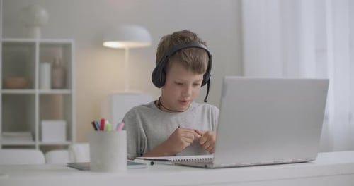 Boy Studying with Laptop and Headphones at Home