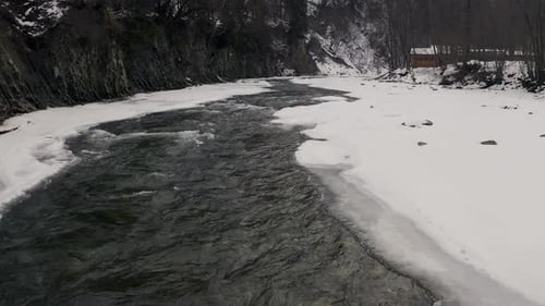 Aerial View in Winter on a Mountain River with a Forest During a Snowfall