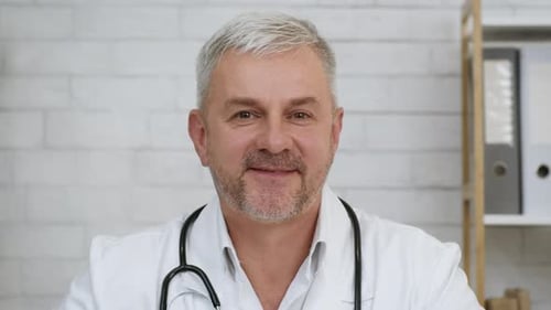 Portrait Of Male Doctor Smiling Sitting In Clinic Office