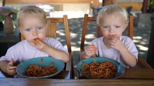 Two Cute Children Eating Spaghetti with a Messy Face