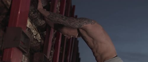 Muscular Person Resting Against Wall at Night