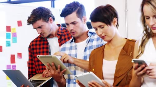 Executives using laptop, mobile phone, digital tablet in office