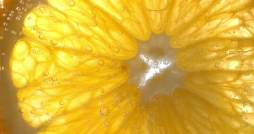 Rundes Stück Orange unter Wasser mit Luftblasen.
