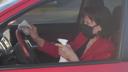 Woman Wipes Steering Wheel with Disinfectant