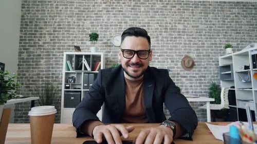 Portrait of Attractive Guy Typing Using Computer in Office Looking at Camera