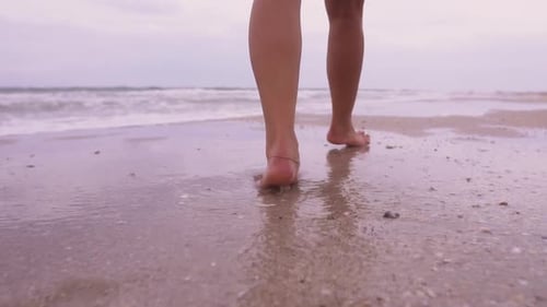 Girl Walks on the Beach on the Background of the Sea