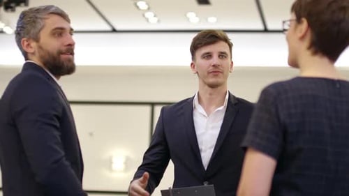 Coworkers Shaking Hands and Talking at Meeting in Office